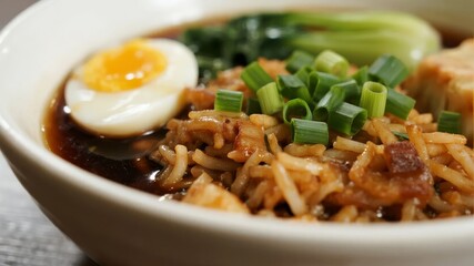 Bowl of ramen with soft-boiled egg, green onions, and vegetables in a rich broth