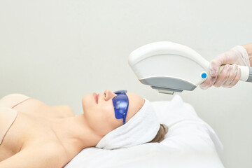 Young caucasian female receiving laser skin treatment wearing protective goggles.