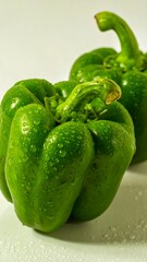 Two fresh green peppers with water droplets