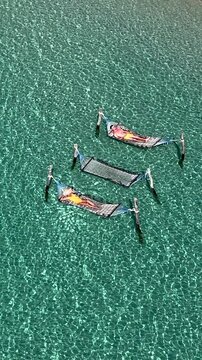 Three hammocks gently sway above crystal-clear waters in Koh Kood. Sunbathers enjoy a tranquil day under the bright sun in a hammoc in the ocean