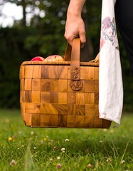 Hand holding a woven wooden basket full of apples