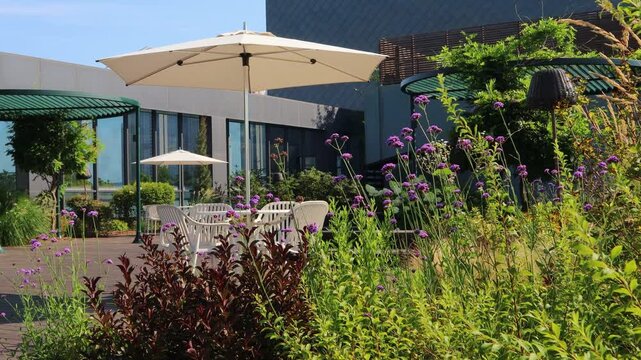 There are parasols and chairs in the urban garden created on the rooftop of a building in the city center.도심의 건물 옥상에 만든 도시정원에 파라솔과 의자가 있습니다.