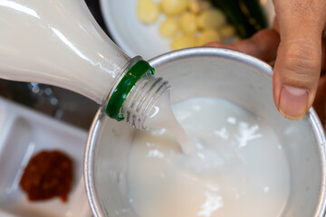 pouring makgeolli into the metal cup