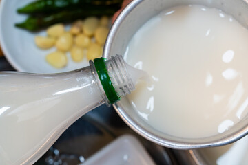 pouring makgeolli into the metal cup