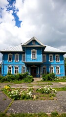 Two-story blue wooden house against a cloudy sky