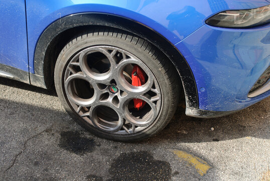 Alfa Romeo Tonale SUV wheel with red brake caliper, showing Misano Blue paint and modern design details