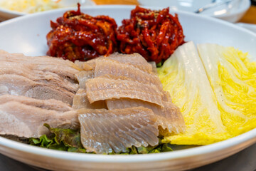 View of Samhap Cuisine composed of boiled pork, fermented skate, spicy radish kimchi and napa cabbage kimchi