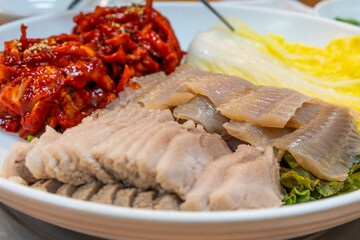 View of Samhap Cuisine composed of boiled pork, fermented skate, spicy radish kimchi and napa cabbage kimchi