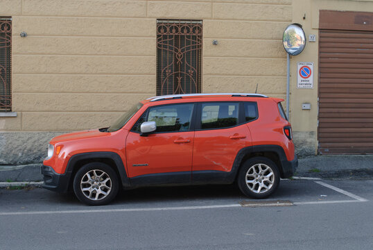 Jeep Renegade SUV parked on urban street next to building with traffic mirror and no standing sign