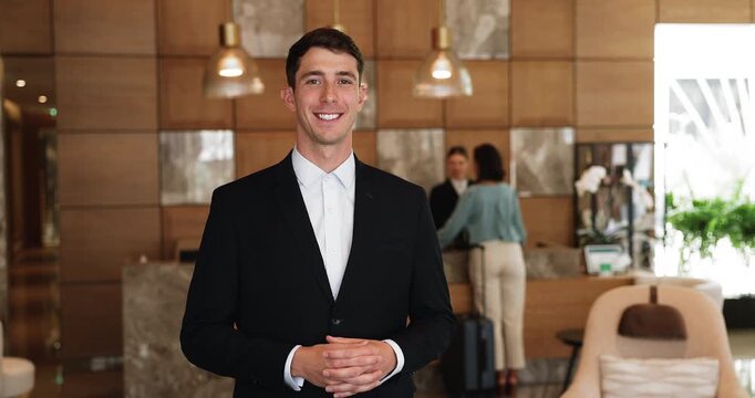 Young man receptionist posing for camera in lobby, portrait
