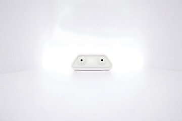 Fototapeta premium White device on a white background with two black dots and a clean minimalist aesthetic look