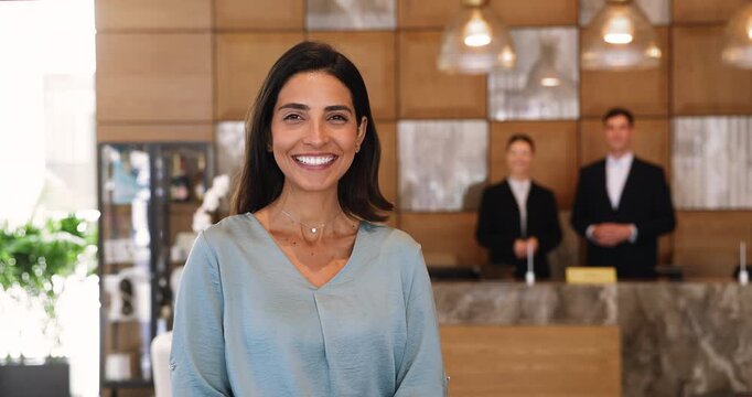 Cheerful woman stands in hotel lobby with happy expression