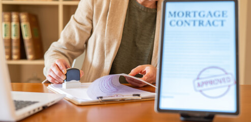 Professional stamping a physical mortgage contract document with an approved stamp, emphasizing real estate finance, home loan approval, and banking agreement processes in an office setting
