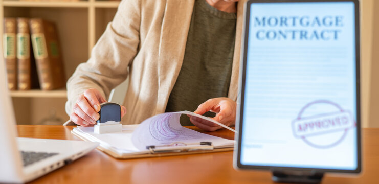 Professional stamping a physical mortgage contract document with an approved stamp, emphasizing real estate finance, home loan approval, and banking agreement processes in an office setting