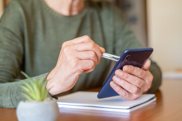 Senior woman's hands holding a smartphone and using a stylus, navigating the digital interface while learning new technologies to stay connected and use modern applications