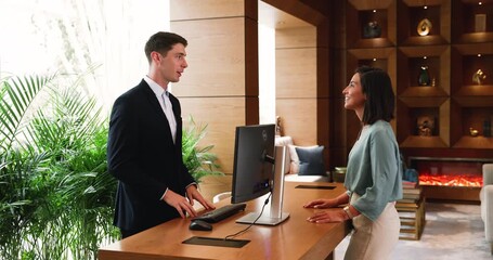 Man receptionist assisting hotel guest at front desk - Powered by Adobe
