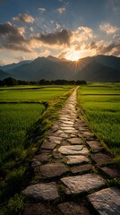 A stone path leads through vibrant green rice fields towards majestic mountains at sunset, creating a serene and picturesque landscape in the countryside