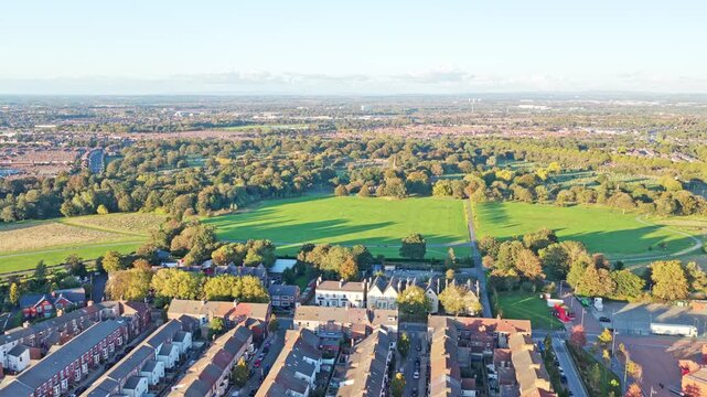 Cinematic aerial drone footage of the neighborhood surrounding Liverpool FC&rsquo;s iconic Anfield stadium, captured during sunset. The golden-hour light highlights residential streets, rows of houses.