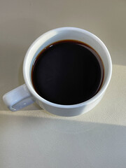 White cup of coffee on the table in a coffee shop.