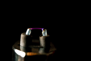 Electric plasma arc spanning between two lighter electrodes against a black background