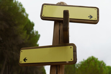 Wooden signpost featuring two blank yellow arrows pointing left and right, offering choice and guidance in ronda,malaga,spain