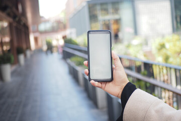 Person showing smartphone on urban walkway during daytime