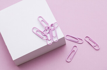 Stack of white memo papers with paper clips on purple background