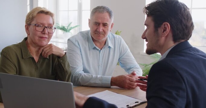 Senior couple talking to real estate broker, handshaking with older family after buying, selling property, spouses smiling thanking bank agent for help ready for signing loan mortgage, agreement 