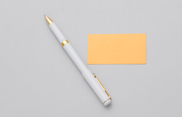Golden business card and pen on gray background