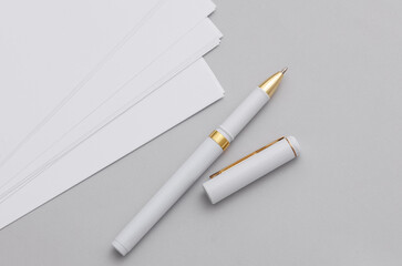 White sheets of paper with pen on gray background. Mockup for design