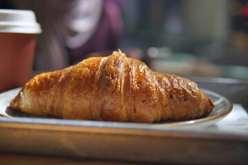 Freshly baked croissant on a plate with coffee