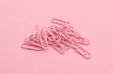 Pink paper clips on a pink background