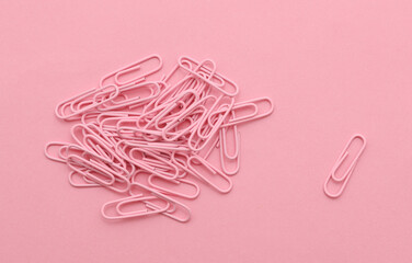 Pink paper clips on a pink background
