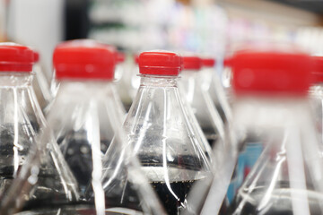 Bottles of soda lined up on store shelf for sale