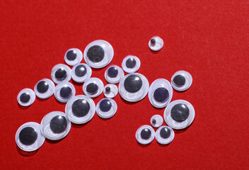 Various sizes of kids art fun googly eyes on red background. Top view