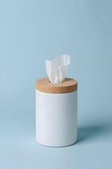Minimalist white tissue container with wooden lid standing on soft light blue background, offering clean modern style for hygiene, skincare, home decor and product presentation settings