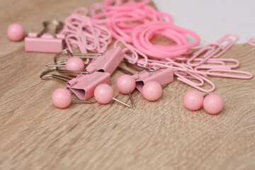 Stationery set of pink paper clips, binders, pins, rubber bands on table