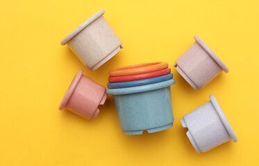 Colored toy bowls pyramid on yellow background