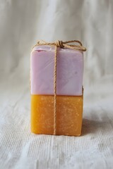 Two handmade soap bars in pastel colors, tied with natural string and placed on a light wooden surface, symbolizing eco-friendly skincare, organic hygiene, and minimalist spa wellness aesthetics.