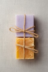 Two handmade soap bars in pastel colors, tied with natural string and placed on a light wooden surface, symbolizing eco-friendly skincare, organic hygiene, and minimalist spa wellness aesthetics.