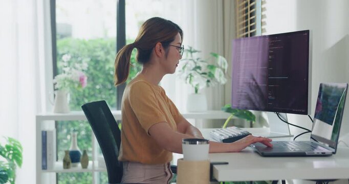 Young adult Asia female freelance eyeglasses typing write prompt AI bot IT app smart program nomad, video game, terminal with coding, user interface, data center on desktop computer at home office.