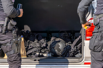 Police equipment in a car trunk, tactical vests, protective helmets, and service gear during officers’ preparation for a field operation.