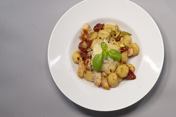 Delicious gnocchi elegantly topped with sundried tomatoes and fresh basil is beautifully arranged on a plate
