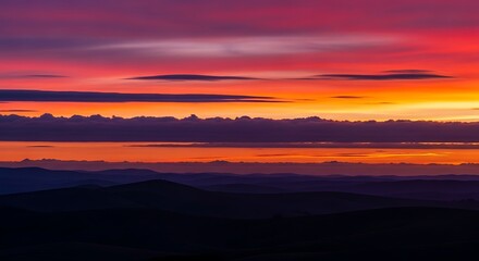 Fototapeta premium Vibrant Sunset Over Rolling Hills with Dramatic Clouds in Fiery Orange and Purple Hues