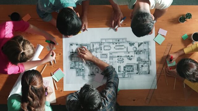 Top view of civil engineer writing and planning by using sticky notes to brainstorm idea. Top down aerial view of business people taking a note at table with project plans and equipments. Symposium.