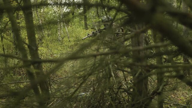 Camouflaged army soldier with AR15 carbine on a scouting mission. Calibrates the front sight of the rifle