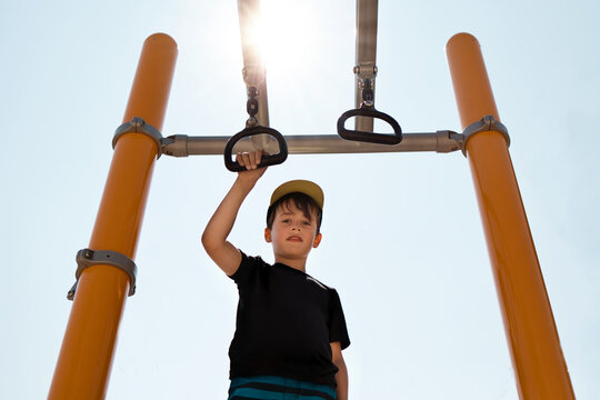 Young Boy Hanging on Monkey Bars at Park