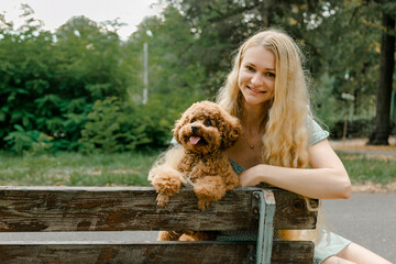 Woman sitting on bench with poodle in park