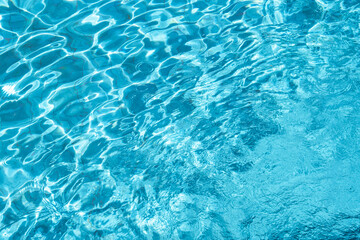 Clear blue water surface with sunlight reflections with ripple texture pattern in swimming pool. 
for summer background,Water splash with light effect for spa,vacation,tropical design,relaxation