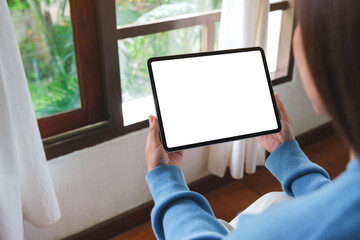 Mockup image of a woman holding tablet with blank desktop white screen at home